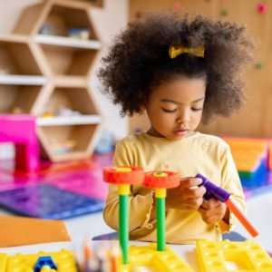 Beautiful African American girl playing with building blocks at the school